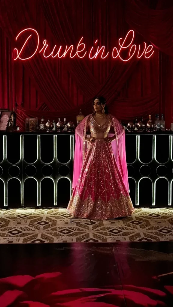 Guest in formal attire standing before an illuminated event bar and celebration sign.