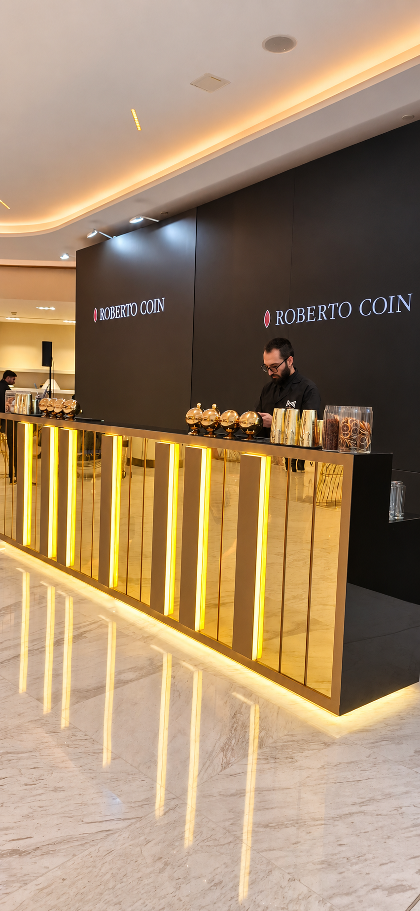 LiquiNeers mixologist behind a gold illuminated bar at a Roberto Coin event