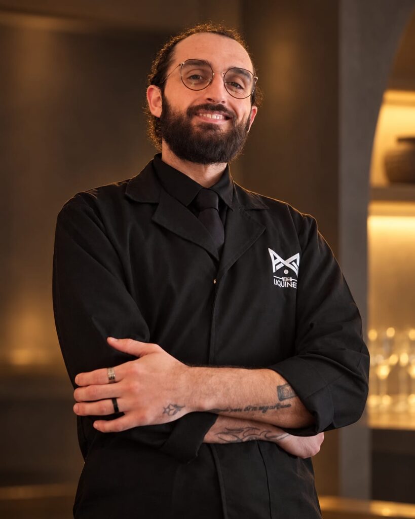 Yamam wearing glasses and a black LiquiNeers uniform with folded arms