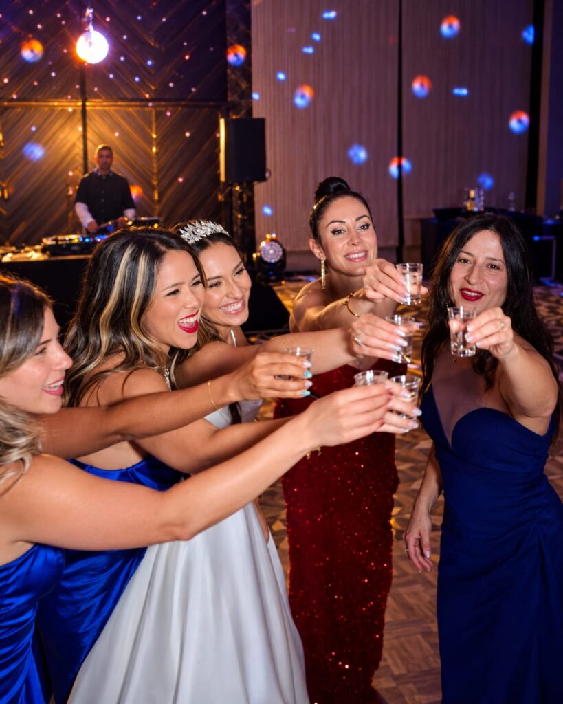 A bride and wedding guests smiling and raising their glasses