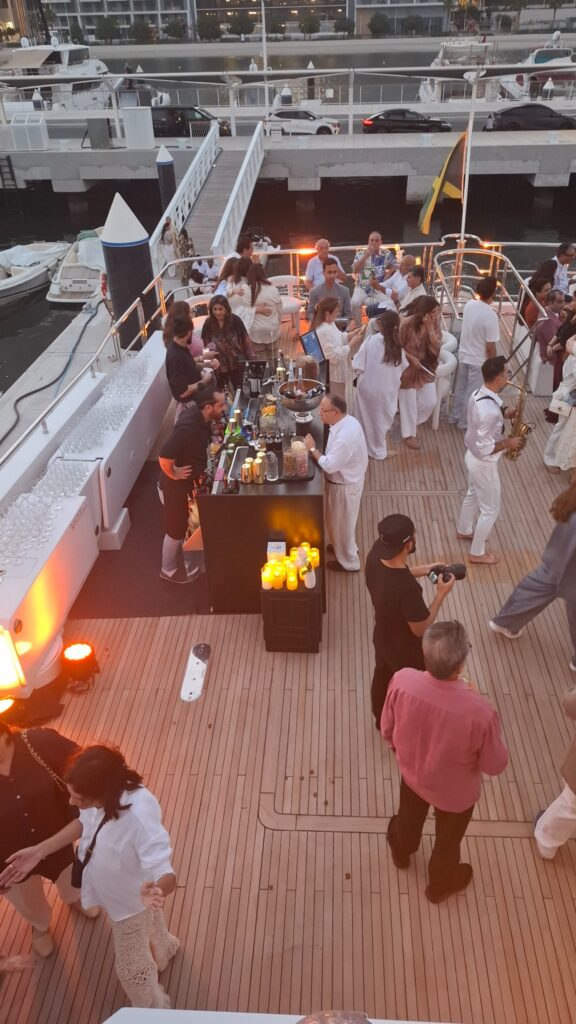 Guests receiving drinks from a bar setup on a yacht deck.
